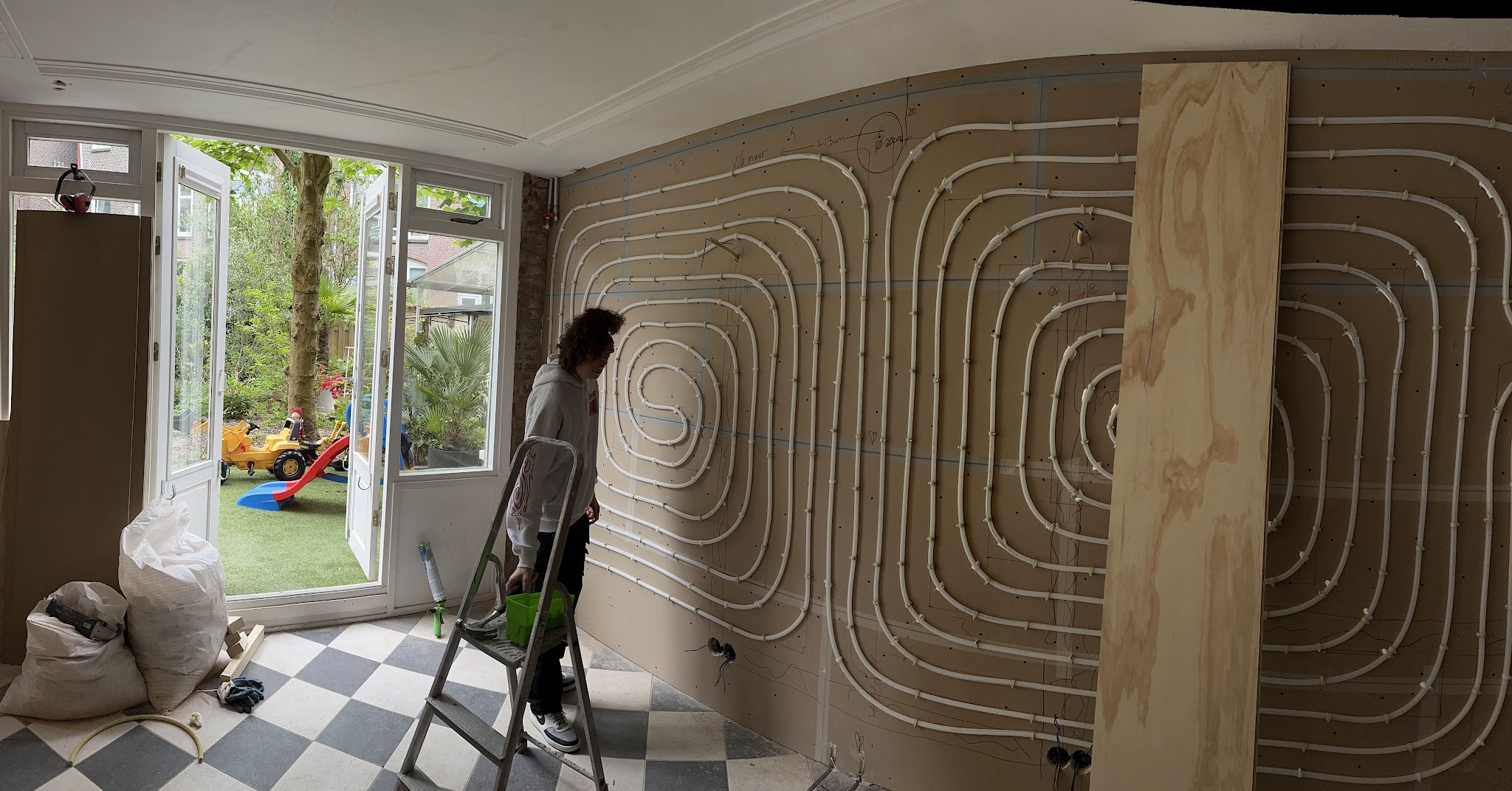 Wandverwarming in lussen op een binnenmuur, met openslaande deuren naar de tuin