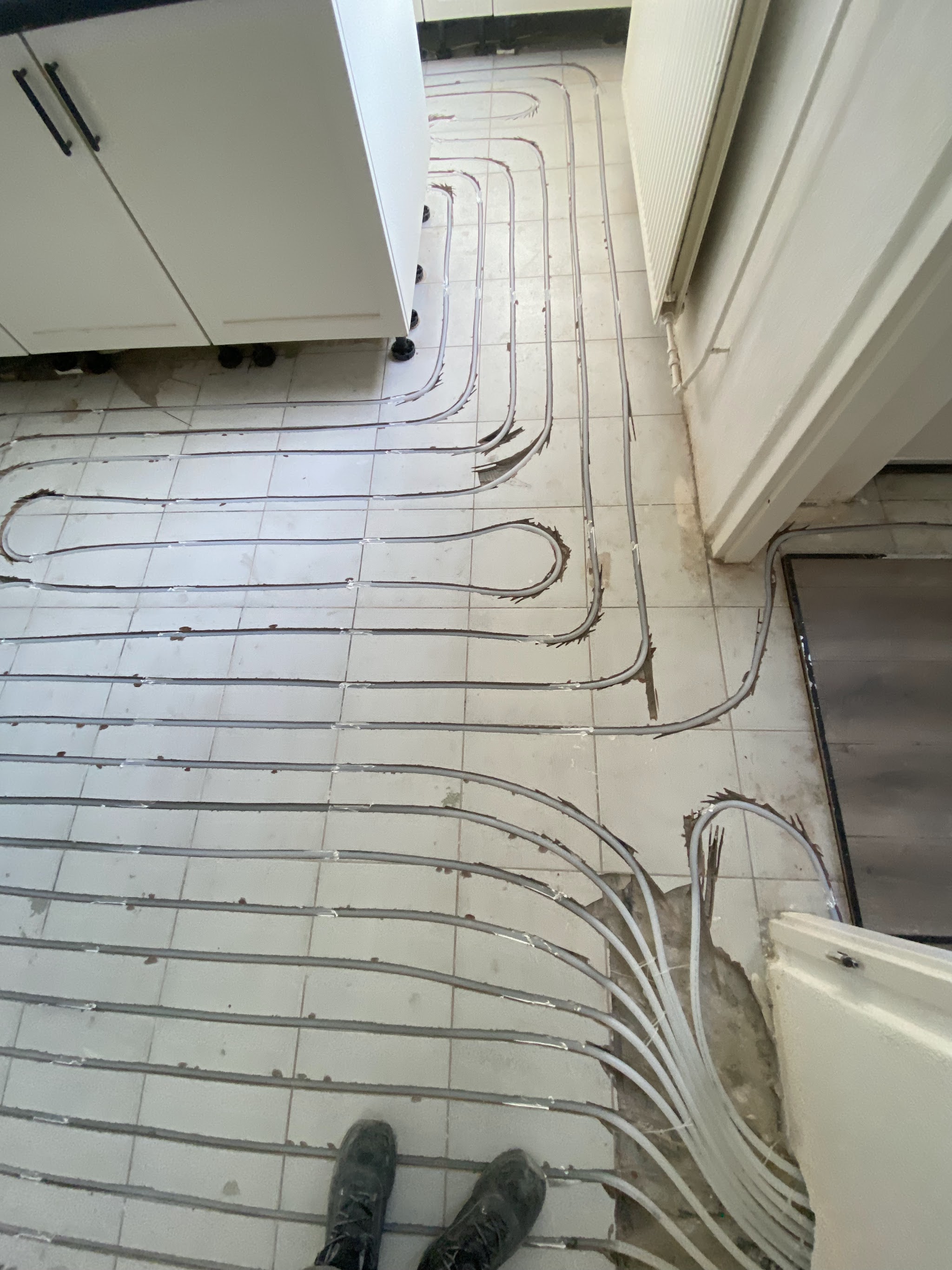 Vloerverwarming die in lussen over de tegelvloer van een keuken is gelegd